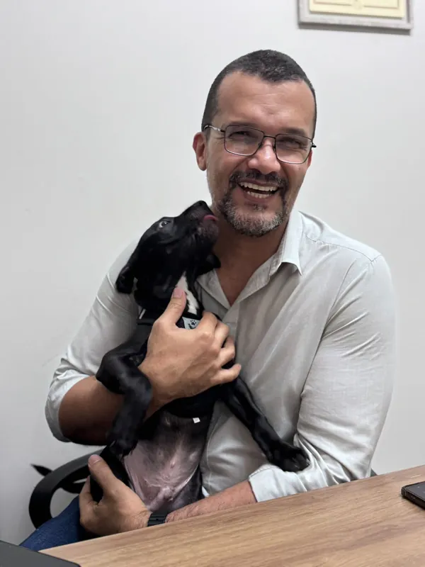 Dr. Ozório com um cão preto no colo