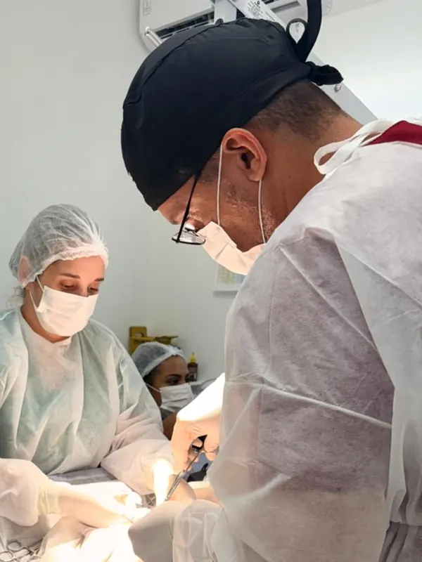 Dr. Ozório em cirurgia, paramentado, com a equipe ao fundo